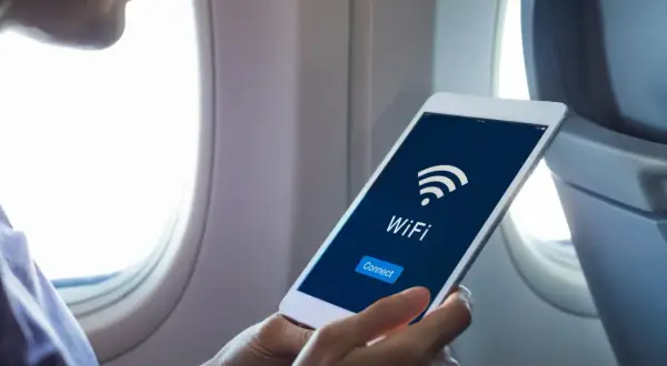 Osoba w samolocie sprawdza na tablecie, czy w Ryanair jest wifi. Widoczny ekran z ikoną wifi i przyciskiem "Connect".