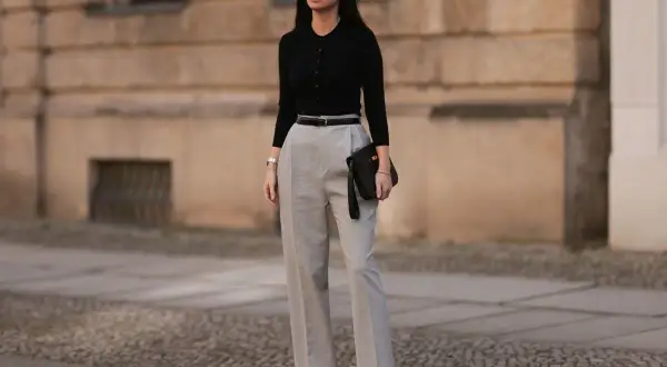 Elegancka stylizacja na 40 urodziny: czarny top, szare spodnie z wysokim stanem, pasek i kopertówka. Idealny look na świętowanie!