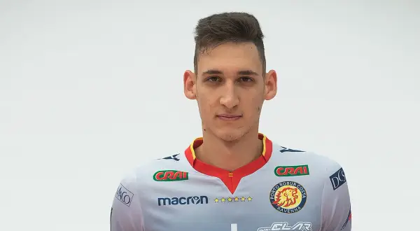 Młody siatkarz z krótką fryzurą, ubrany w szary strój z logo Porto Robur Costa Ravenna.