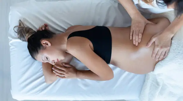 Une femme enceinte reçoit un massage du dos. Apprenez comment masser son périnée pour une préparation à l'accouchement en douceur.