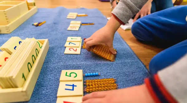 Dzieci bawią się matematycznie, układając klocki z cyframi i koraliki.