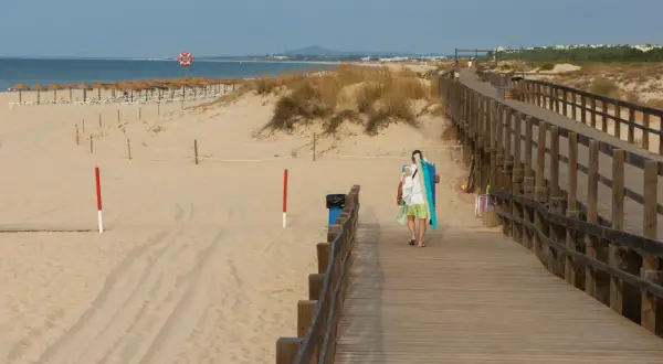 Drewniany deptak prowadzi na piaszczystą plażę. W oddali widać morze i rzędy parasoli. To idealne miejsce na spacer i odkrywanie atrakcji Grzybowa.
