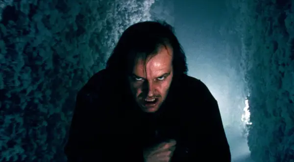Jack Nicholson z przerażającą miną w ciemnym korytarzu.