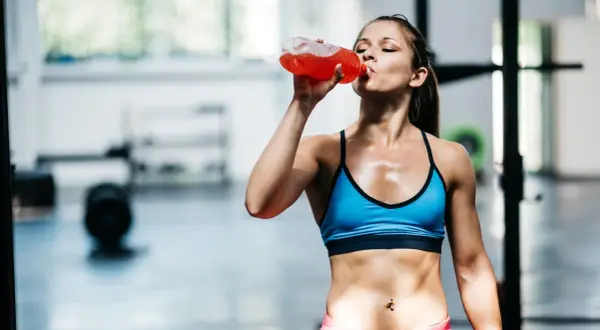 Eine Frau trinkt nach dem Training ein isotonisches Getränk. Es hilft, den Flüssigkeits- und Elektrolythaushalt auszugleichen.