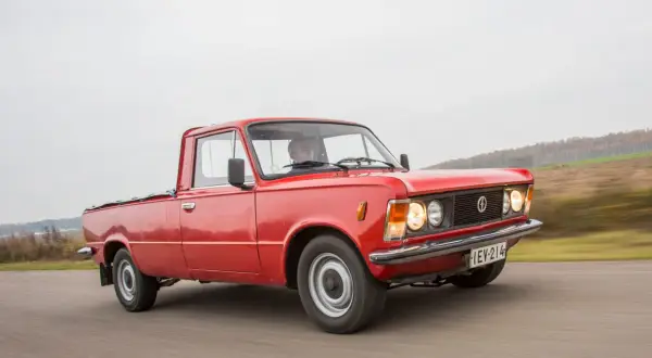 Czerwony fiat 125p pickup w ruchu, z kierowcą za kierownicą. Klasyk na drodze.