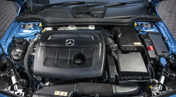 Motor de un Mercedes Clase A 180 gasolina, con su tapa negra y el logo de la estrella.