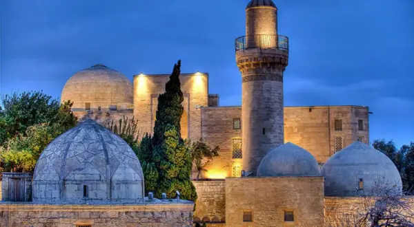 Meczet z minaretem i kopułami w Baku, symbol azerbejdżańskiej religii, oświetlony nocą.