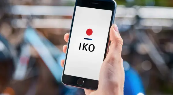 Dłoń trzyma smartfon z logo IKO. Dowiedz się, jak założyć IKO w telefonie, by wygodnie płacić.