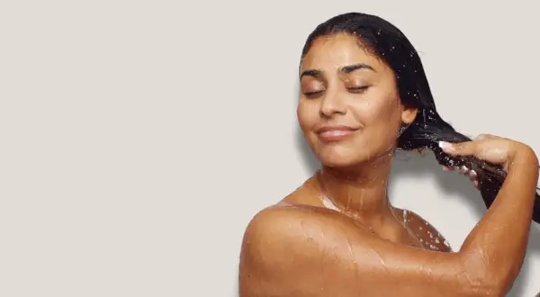 Frau mit geschlossenen Augen, die sich die nassen Haare wäscht. Sie genießt die Pflege, als würde sie ihre Haare nur mit Conditioner waschen.