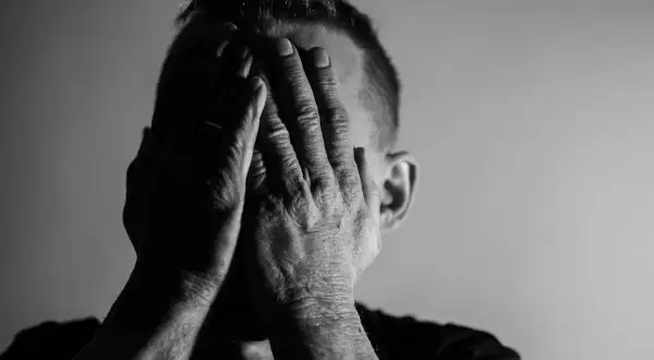 Mężczyzna zakrywa twarz dłońmi, co może symbolizować przytłoczenie i zmęczenie, jedne z objawów neurastenii.