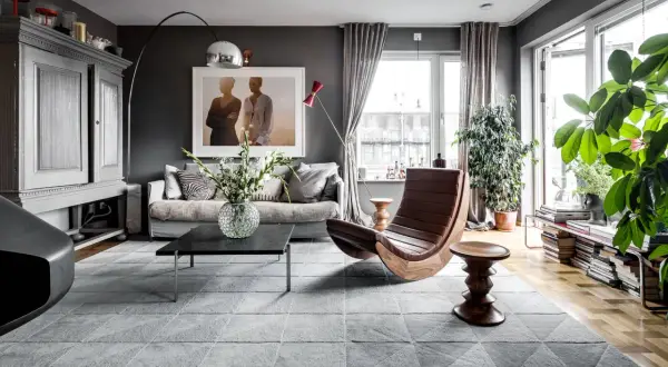 Stilvolles Wohnzimmer in Grau mit gemütlicher Couch, Design-Sessel und viel Grün. Tolle wohnzimmer grau ideen für ein modernes Zuhause.