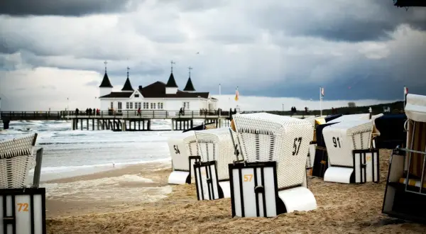Strandkörbe am Ostseestrand mit Pier und Gebäude im Hintergrund. Perfekte ausflugsziele ostsee bei schlechtem wetter, um dem Wind zu trotzen.