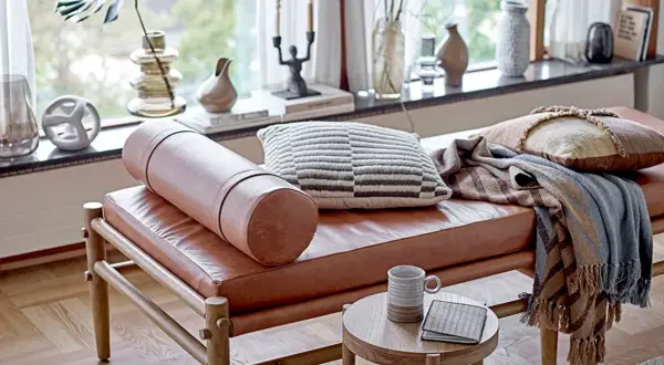 Un cómodo espacio de meditación con un banco de cuero, cojines texturizados y mantas cálidas.