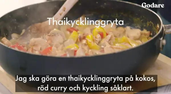 En thaikycklinggryta med kycklingbitar, gul och röd paprika i en krämig sås i en stekpanna.