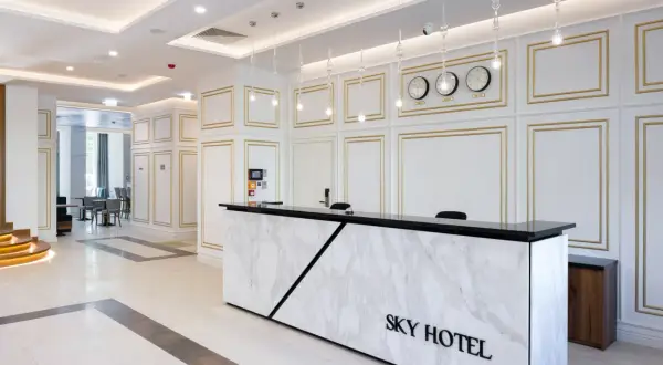 Eleganckie lobby hotelu Sky Kraków z marmurowym recepcjonistą i zegarami światowymi.