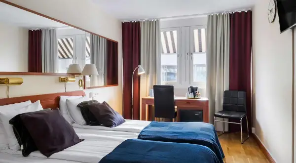 Dubbelrum med två sängar, mörkläggningsgardiner, skrivbord och spegel. Ett bekvämt och funktionellt rum på detta **sure hotel**.