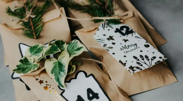 Sacchetti marroni per realizzare calendario dell'avvento fai da te, decorati con pigne, foglie e numeri.