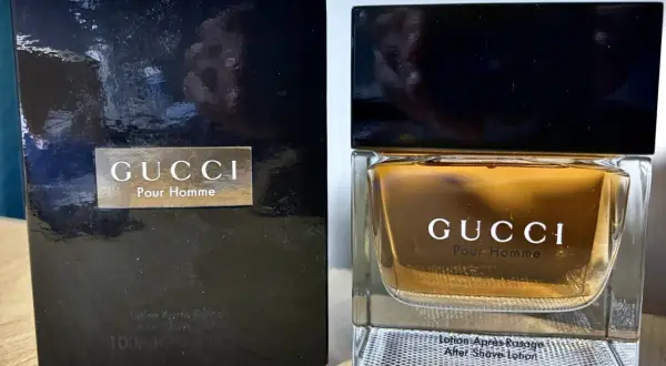 Elegancki zestaw z wodą po goleniu Gucci Pour Homme. Złocisty płyn w szklanym flakonie i czarne opakowanie.
