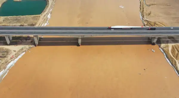 Most gigantycznego łopaty wiatraka transportowany przez most nad mętną wodą rzeki Huang He.