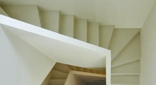 Escalera moderna de diseño minimalista con revestimiento blanco y peldaños de madera clara.