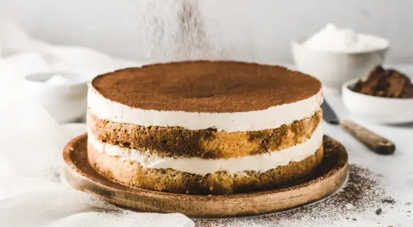 Ein köstlicher Tiramisu-Kuchen wird mit Kakaopulver bestäubt.