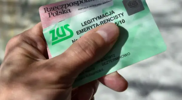 Dłoń trzyma zieloną legitymację emeryta-rencisty ZUS. Dokument potwierdza uprawnienia do świadczeń.