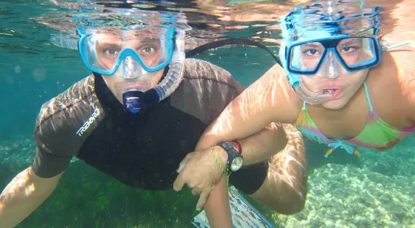 Padre e hija disfrutan del snorkel en la playa de los Muertos, explorando el fondo marino.