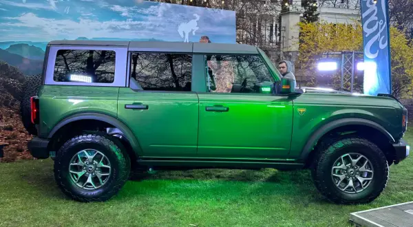 Zielony Ford Bronco prezentuje się imponująco na tle krajobrazu z dzikim koniem.