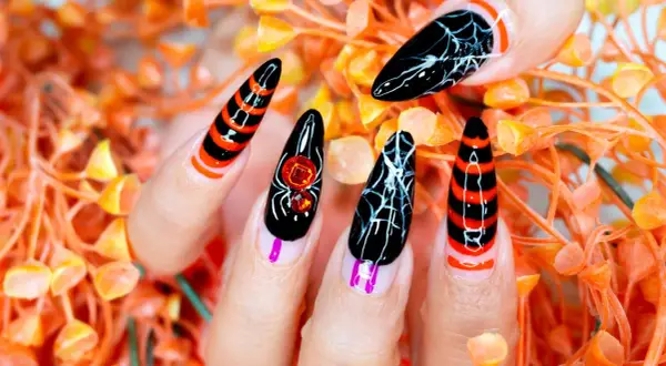 Przerażające paznokcie halloweenowe: czarne z pajęczynami, paskami i ozdobami w kształcie pająka.