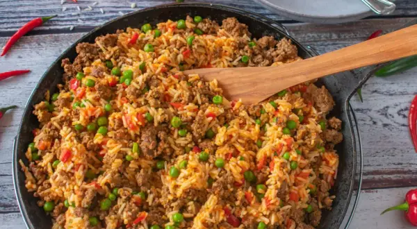 Herzhafte hackfleisch reis pfanne mit Erbsen und Paprika, garniert mit Chilischoten. Ein köstliches Gericht für die ganze Familie.