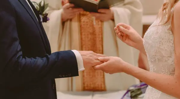 Para ślubna wymienia obrączki. Czy sakrament bierzmowania jest potrzebny do ślubu? Kapłan błogosławi parę.