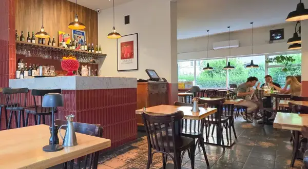 Wnętrze restauracji z barem, stołami i ludźmi jedzącymi posiłek. Klimatyczna restauracja it.