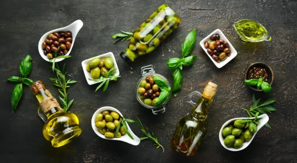 Diverse olive, in ciotole e bottiglie, con olio e basilico. Chissà quanto pesa un oliva, ma sono perfette per un antipasto.