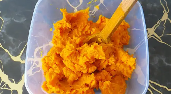 Jasne, oto opis:

Pomarańczowe, gęste puree z dyni hokkaido w plastikowym pojemniku, z drewnianą łyżką.
