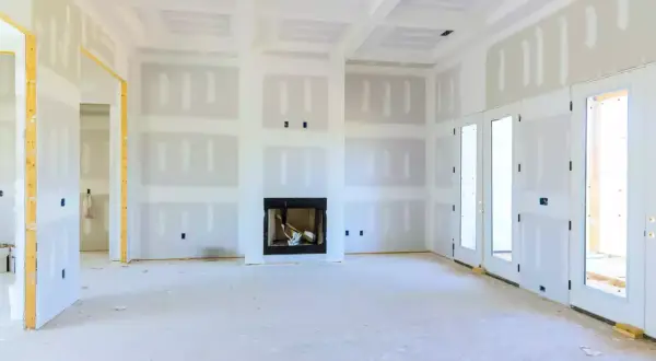 Interno di una casa in costruzione con pareti e soffitti in cartongesso coibentato, camino e porte a doppio battente.