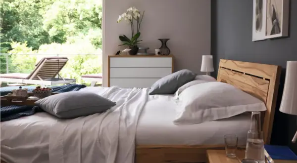 Gemütliches Schlafzimmer mit anthrazit Wand, Holzbett und Blick ins Grüne.