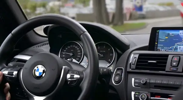 Wnętrze BMW z kierowcą, który zdaje egzamin kontrolny po utracie prawa jazdy za punkty. Nawigacja pokazuje trasę.