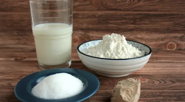Milch, Mehl, Zucker und ein Stück Hefe liegen bereit. Die Grundzutaten für einen perfekten Hefeteig.