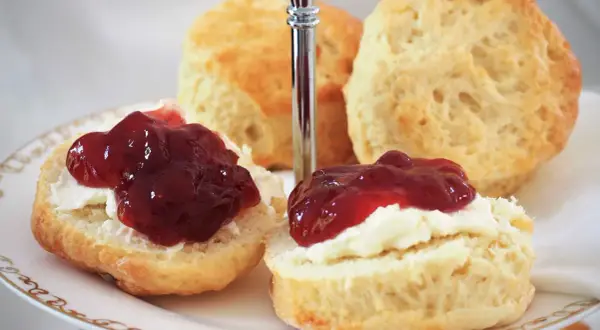 Zwei Scones mit Clotted Cream und Marmelade auf einer Etagere. Ein köstliches Rezept für Scones, das man unbedingt ausprobieren muss!