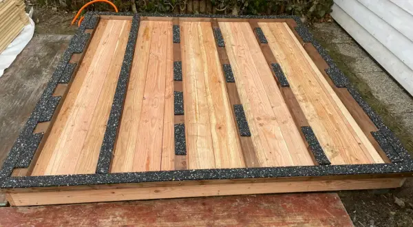 Holzboden für Gartenhaus mit schwarzer Feuchtigkeitssperre am Boden.