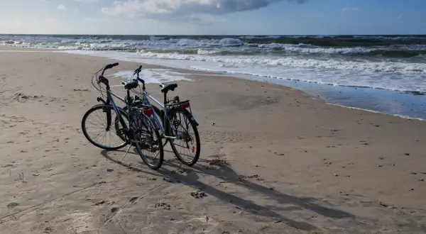 Dwa rowery na piaszczystej plaży nad Bałtykiem. Idealne, by jak zaplanować trasę rowerową wzdłuż polskiego wybrzeża etapami.