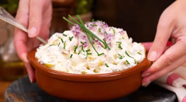 En skål med krämig potatissallad, toppad med rödlök och gräslök. Ett ljuvlig potatissallad recept som passar till allt!