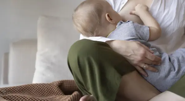 Ciepły dzień karmienia piersią. Mama tuli dziecko, które pije mleko.