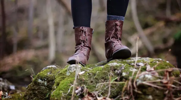 Voeten in bruine laarzen op een mosbegroeide steen. Een reflectie van de natuurlijke wereld, misschien een hsp hss test in de buitenlucht.