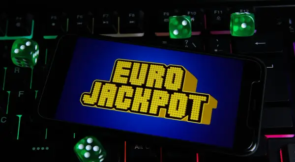 Zielone kostki do gry i ekran telefonu z napisem "EURO JACKPOT" na podświetlanej klawiaturze. Czy to przypadek, dlaczego te same euroliczby wypadły w dwóch losowaniach pod rząd?
