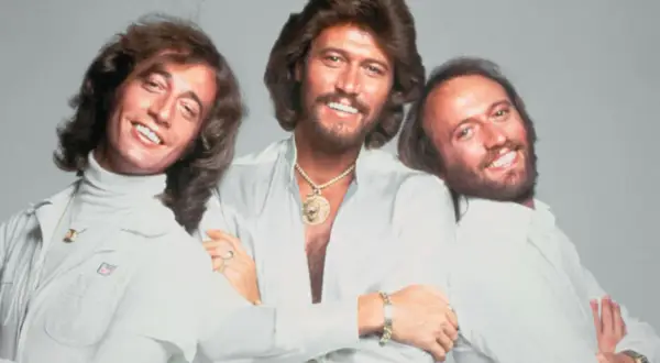 Trzej bracia z Bee Gees, Barry, Robin i Maurice Gibb, uśmiechają się do zdjęcia. Kto żyje? Barry i Robin.