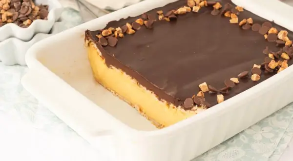 Tarta de natillas y galletas con cobertura de chocolate y trocitos de galleta y chocolate.