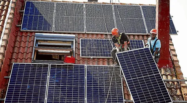 Instalación de placas solares en Extremadura. Dos operarios colocan un panel solar en un tejado, aprovechando la subvención.