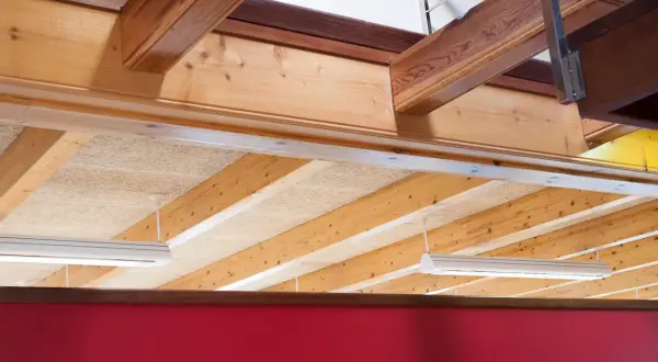 Detalle constructivo de forjado de madera con vigas expuestas y paneles aislantes.