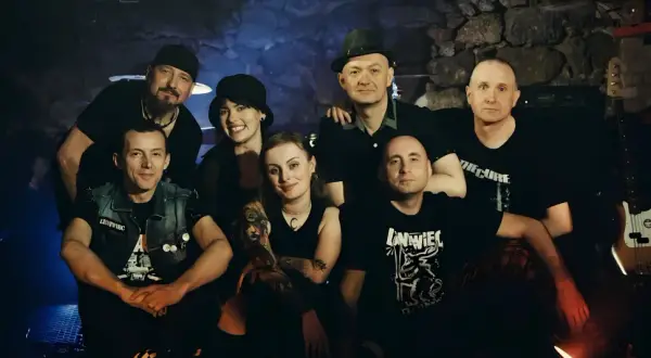 Grupa przyjaciół, zespół Leniwiec, pozuje do zdjęcia w mrocznym wnętrzu.
